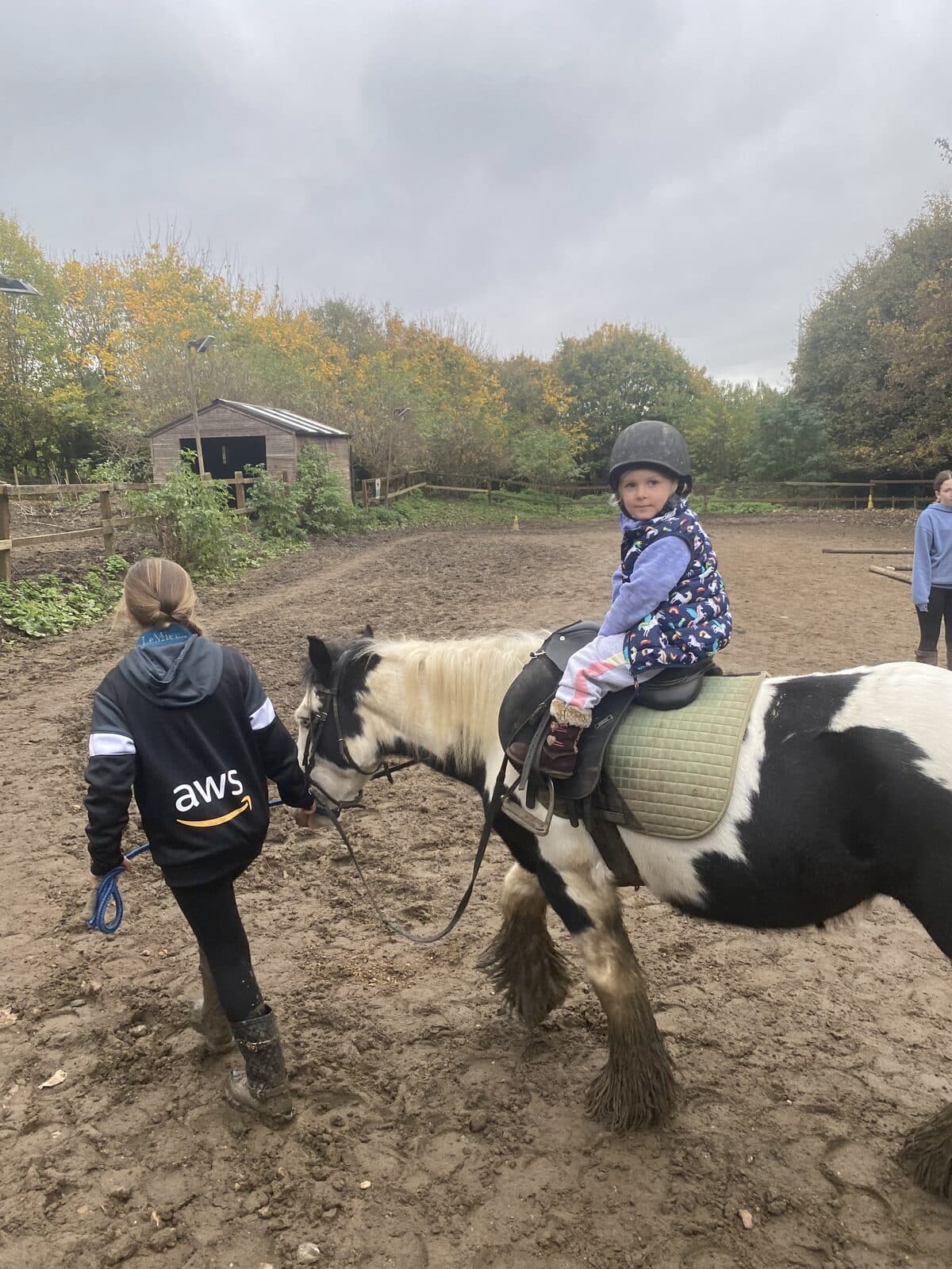 A child being led on a piebald pony at a UK riding centre.